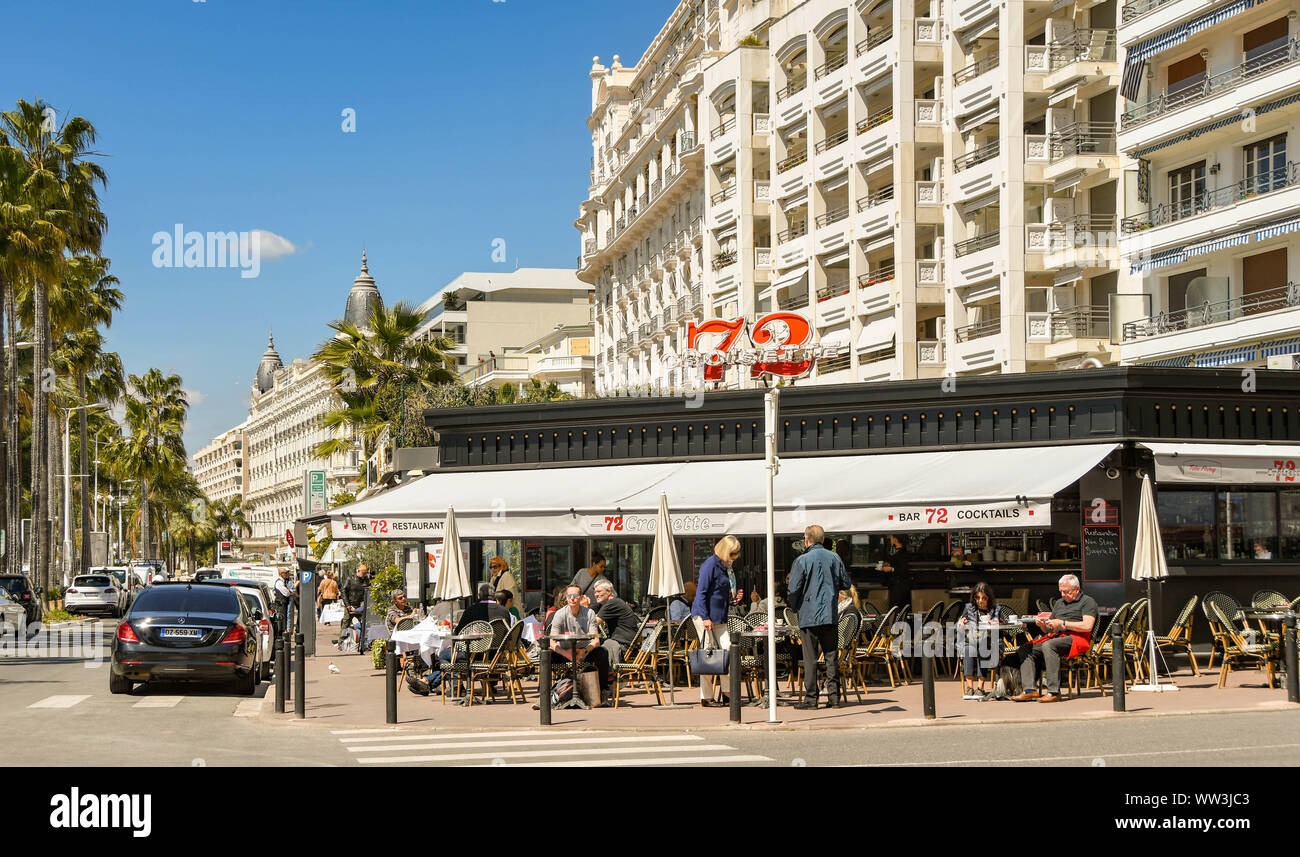 CANNES, FRANCE - APRIL 2019: People sitting at tables outside the Bar 72 cafe restaurant on the seafront road in Cannes Stock Photo