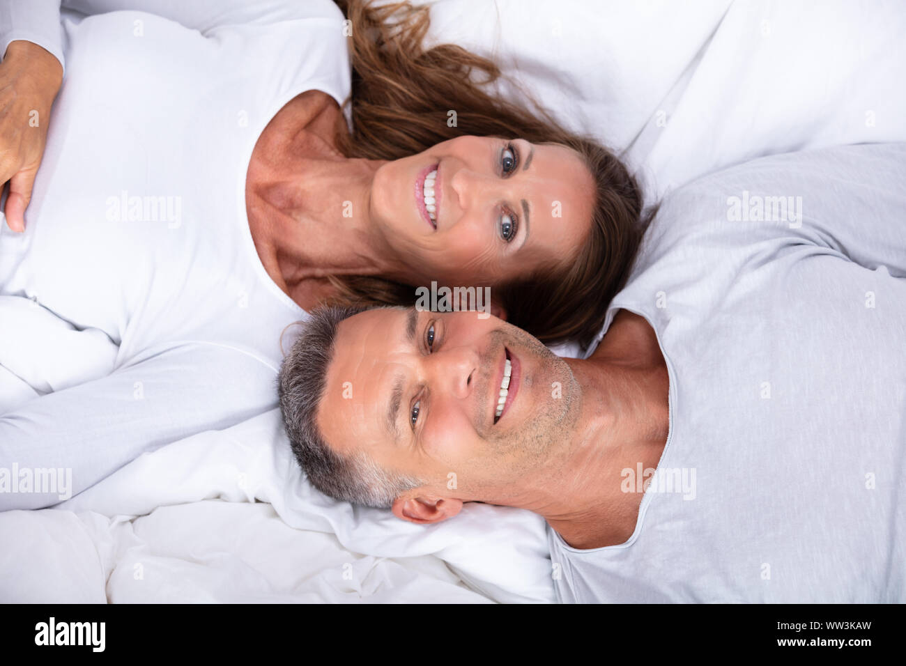High Angle View Of Happy Mature Couple Lying On Bed Stock Photo