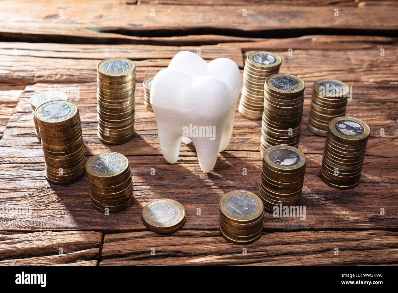 White Healthy Human Tooth And Stacked Coins On Wooden Desk Stock Photo