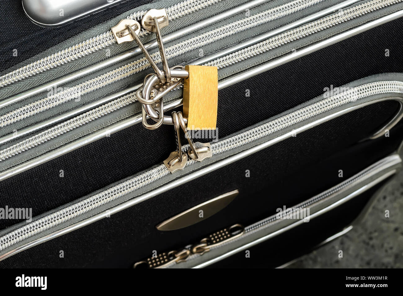 Zippers locked with a padlock on a black travel suitcase. Protect the
