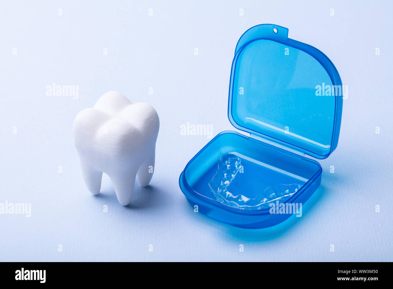 White Dental Model And Transparent Mouth Guard In Case Over Blue Surface Stock Photo