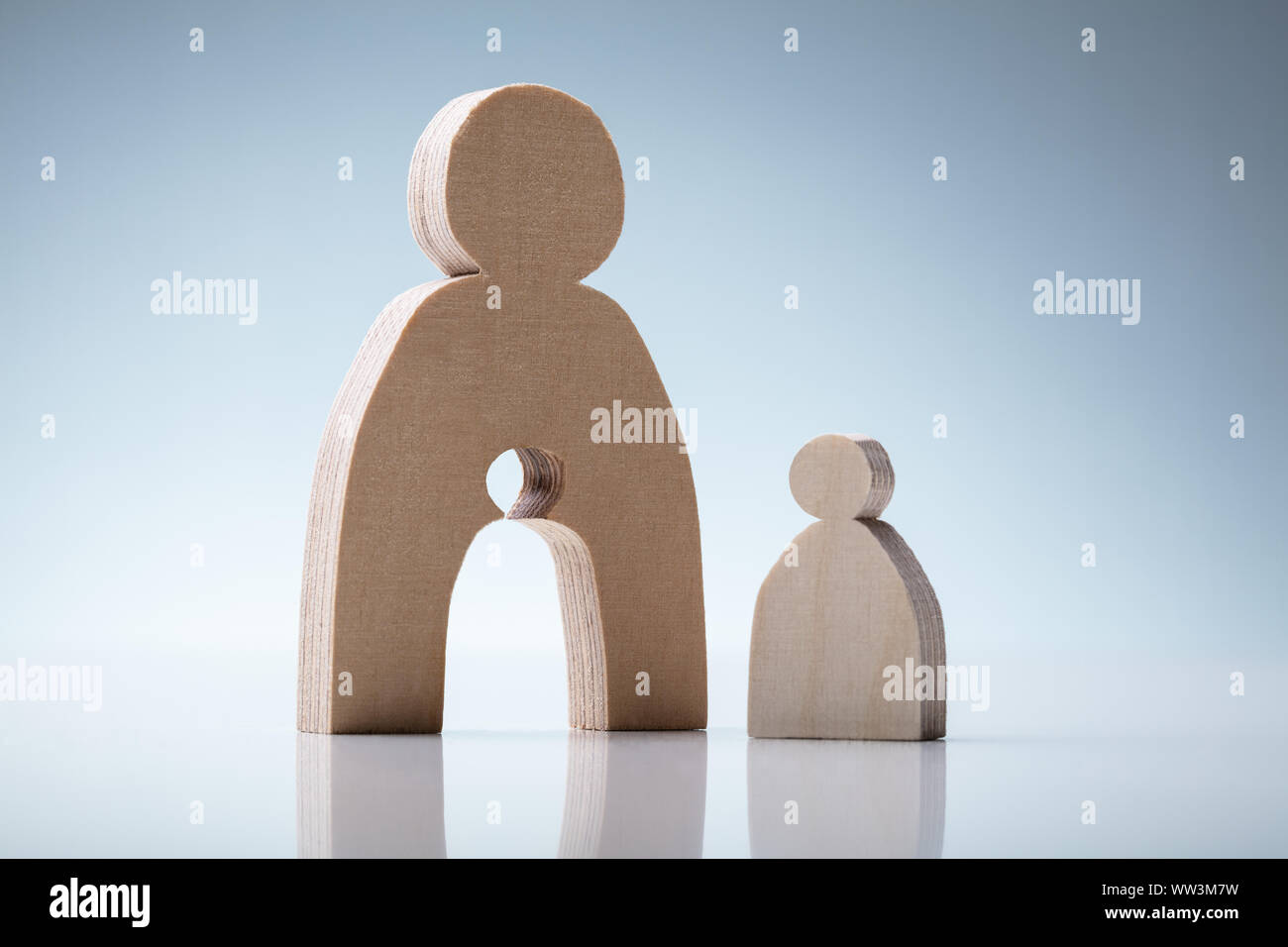 Wooden Figures Showing Mother And Child Concept Over Reflective Desk Stock Photo