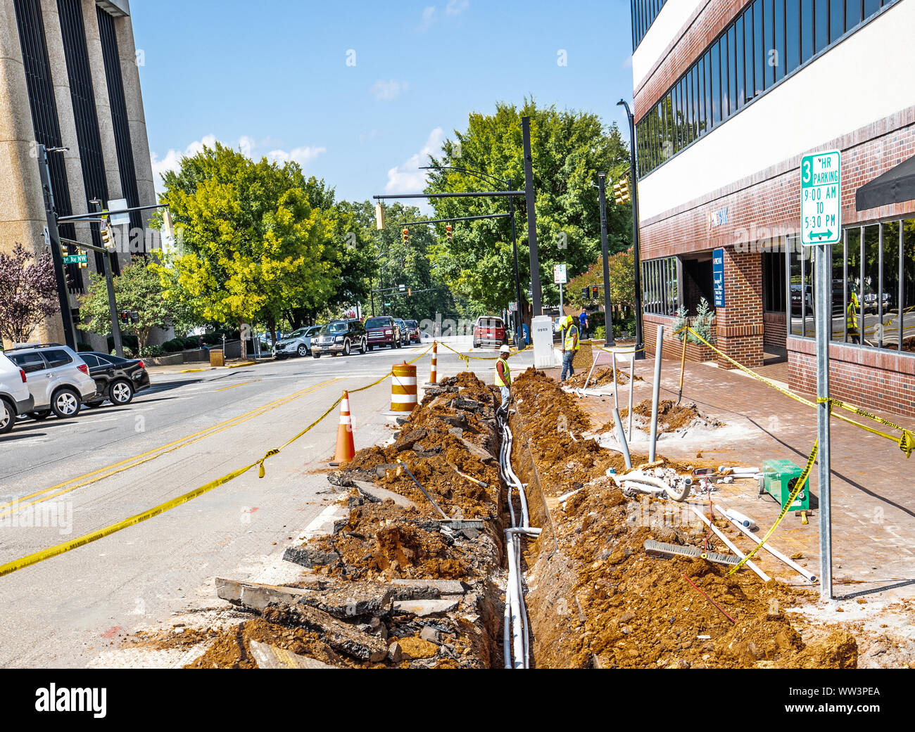 HICKORY, NC, USA-3 SEPT 2019: Workers laying underground cable in a ditch on a city street. Stock Photo