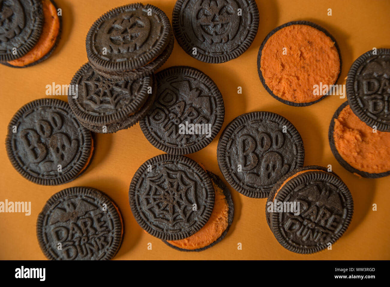 Halloween chocolate cookies with a orange creme filled center some exposed  looking down close up on a orange background Stock Photo - Alamy