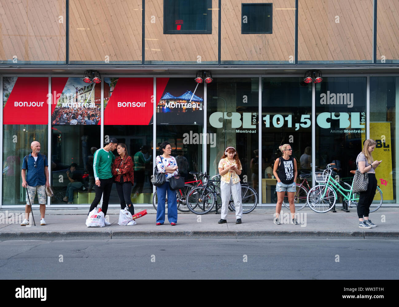 Montreal, Canada. Jul 2019. Canadians at bus stop waiting for public transportation. Stock Photo