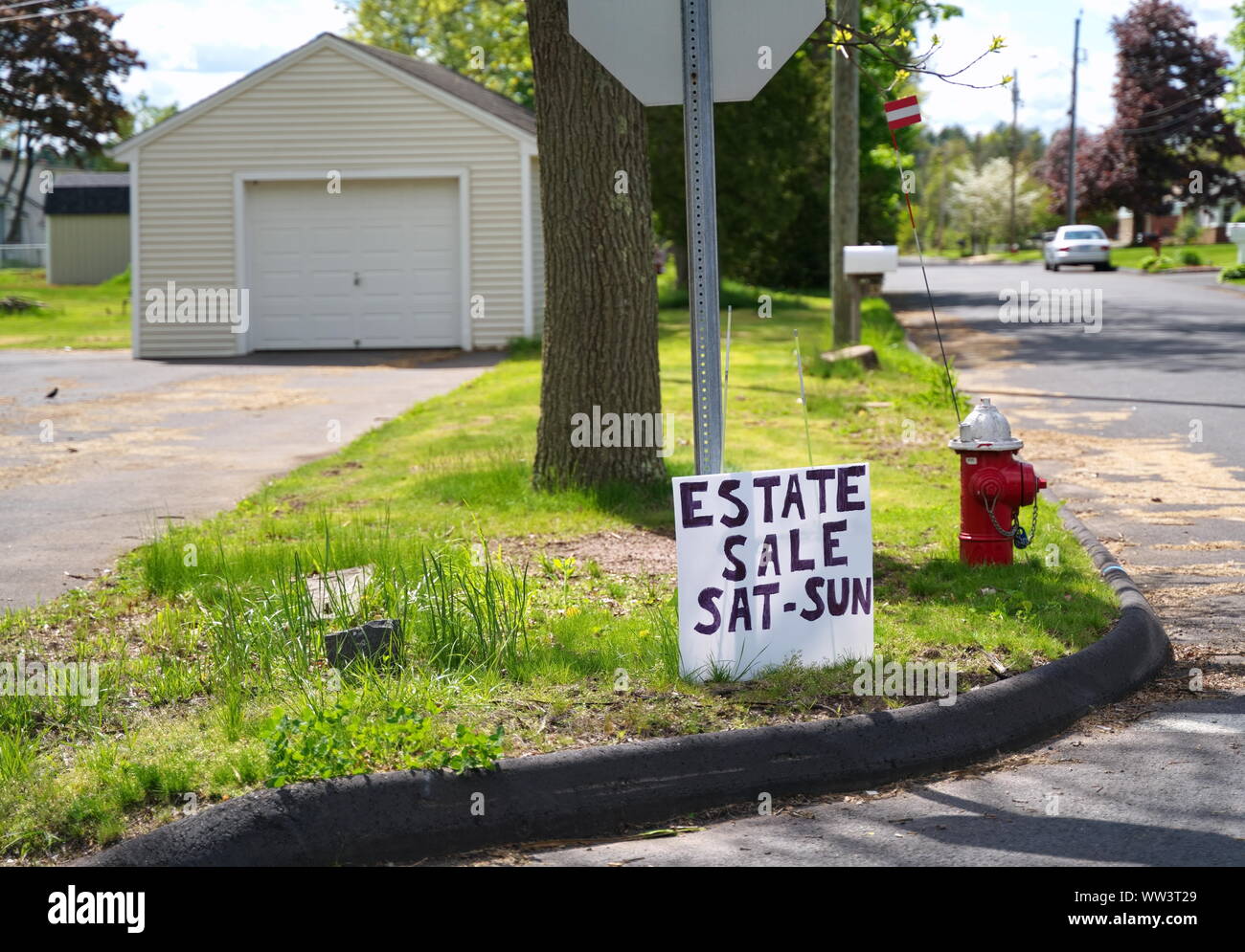 Neighborhood estate sale sign leaning against a stop sign signaling