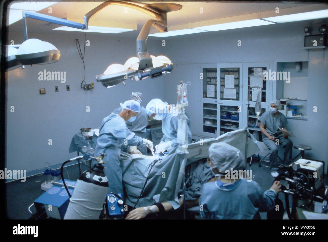 Surgeons performing knee replacement in sterile surgical scene. Stock Photo