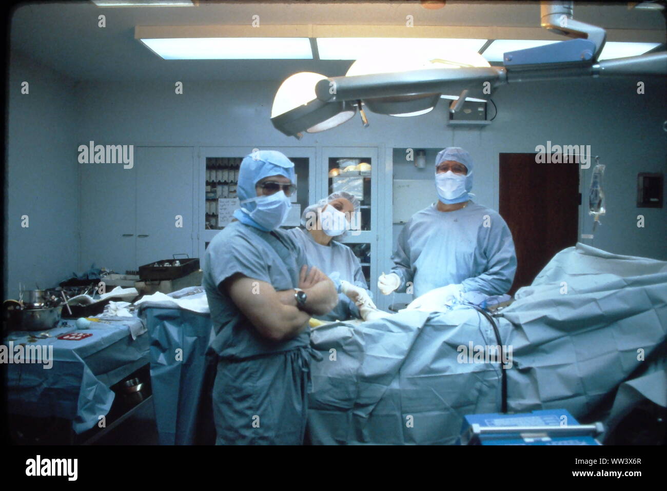 Surgeons performing knee replacement  in sterile surgical scene. Stock Photo