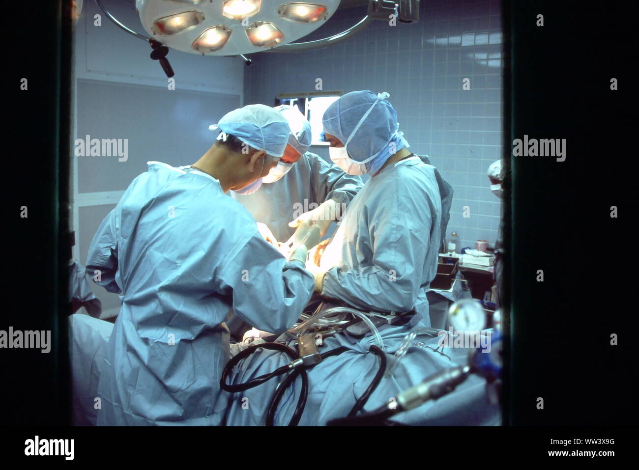 Surgeons performing knee replacement  in sterile surgical scene. Stock Photo