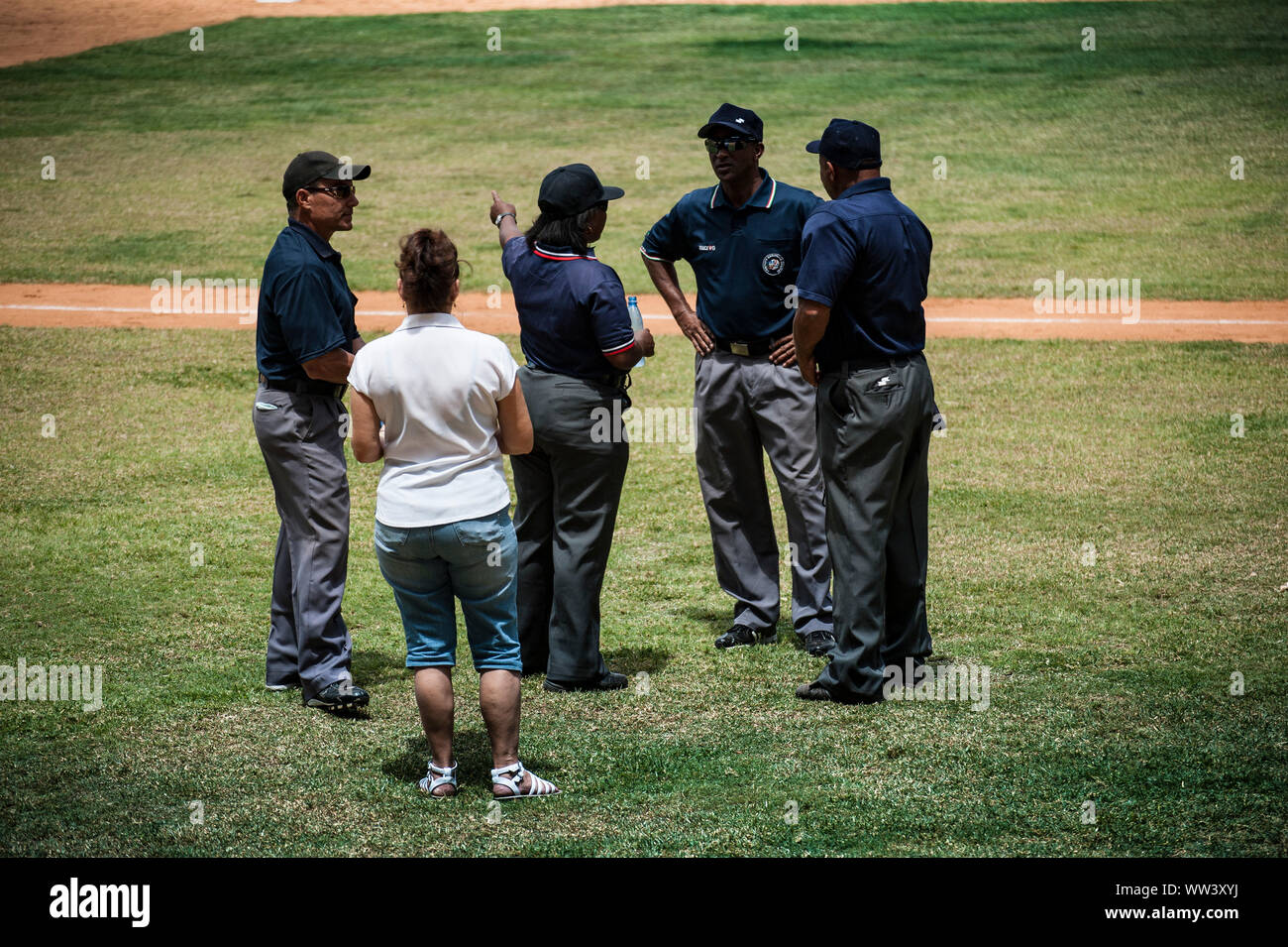 Umpires, one being female, gather on field during a baseball game in Havana, Cuba Stock Photo