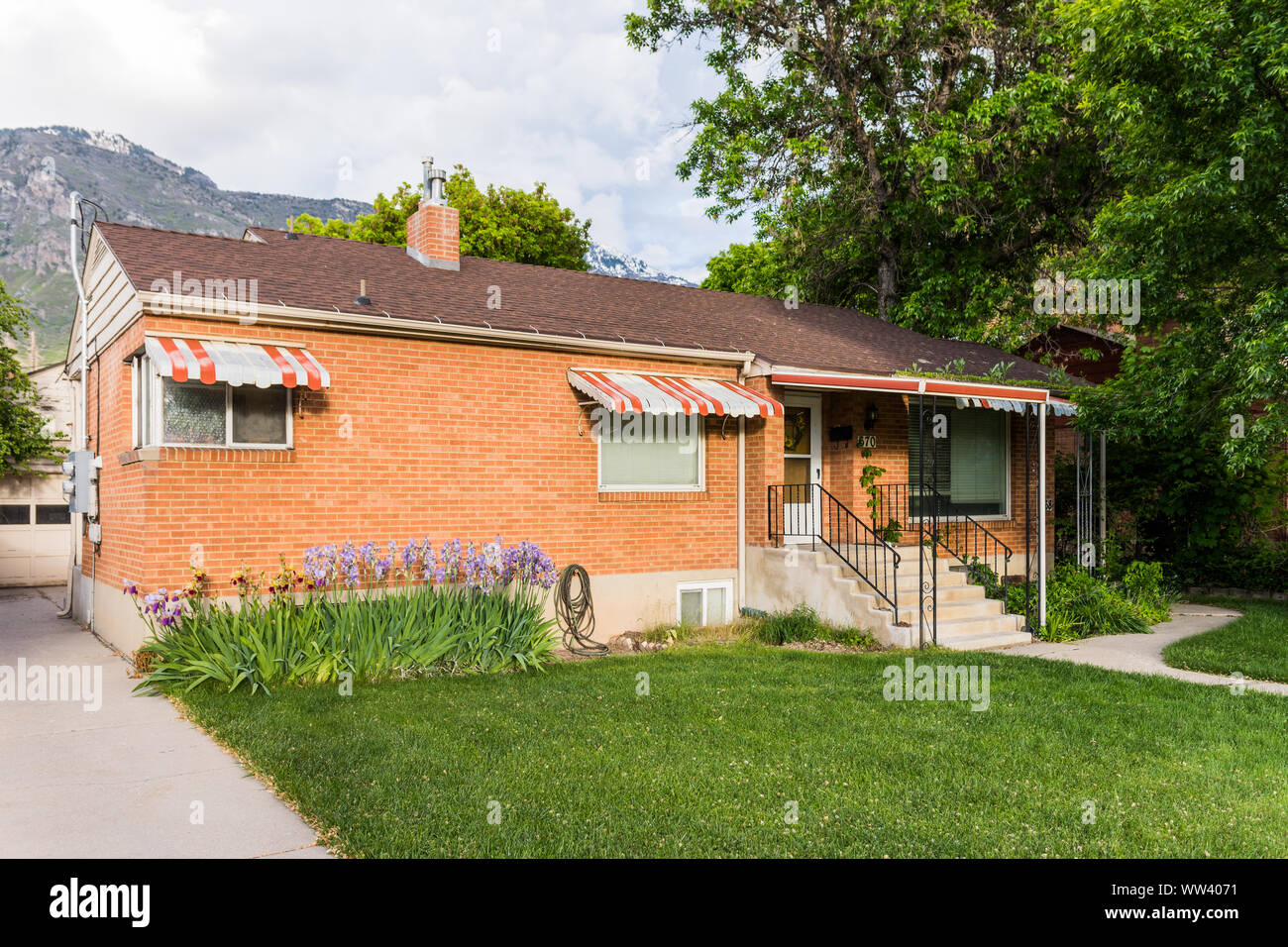 Brick house with old style window awnings, with well kept yard and