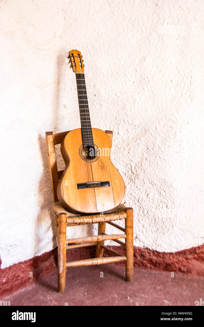 Acoustic guitar placed on a chair leaning against a wall hires stock