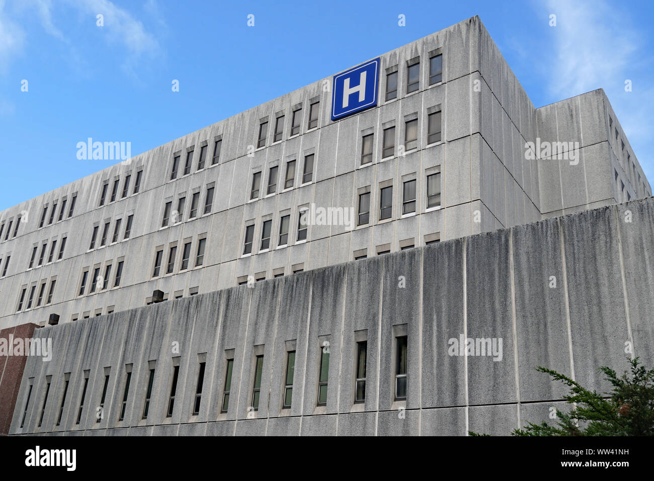 Large grey concrete building with H sign for hospital Stock Photo