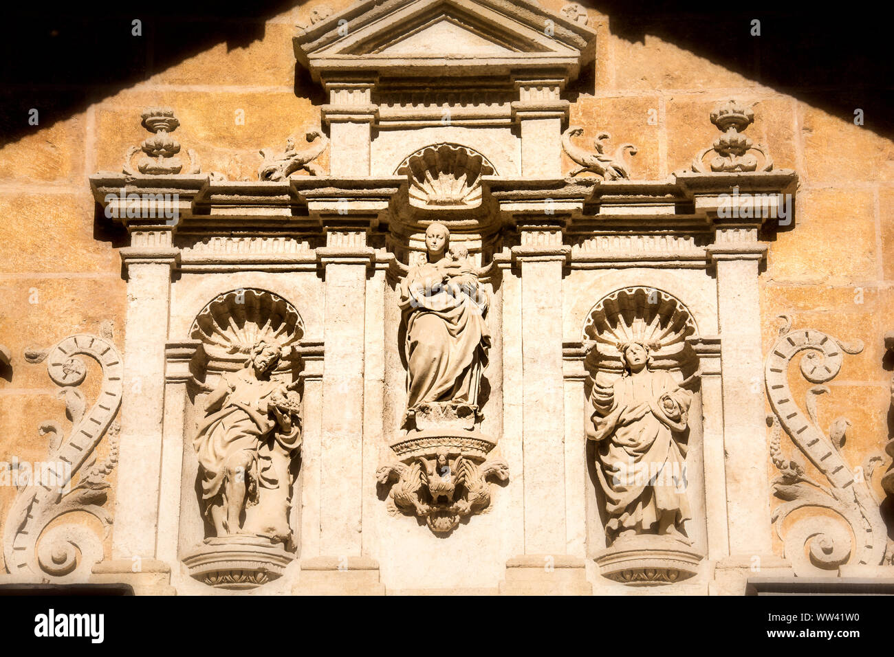 Exterior wall of the Granada Cathedral in Granada, Spain featuring ornate, religious-oriented symbols and figures. Stock Photo