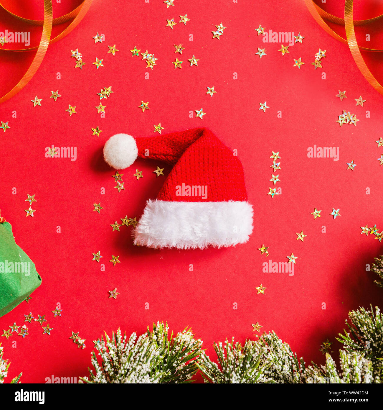 Christmas gift, Santa hat, gift, tree branches on red background with ...
