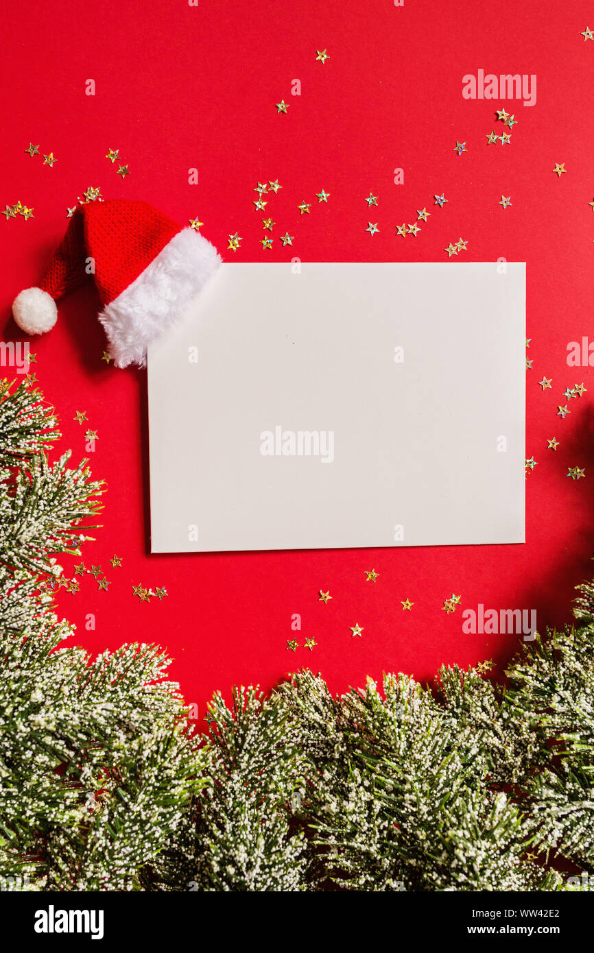 Blank of paper with Santa hat, gift, tree branches on red background ...