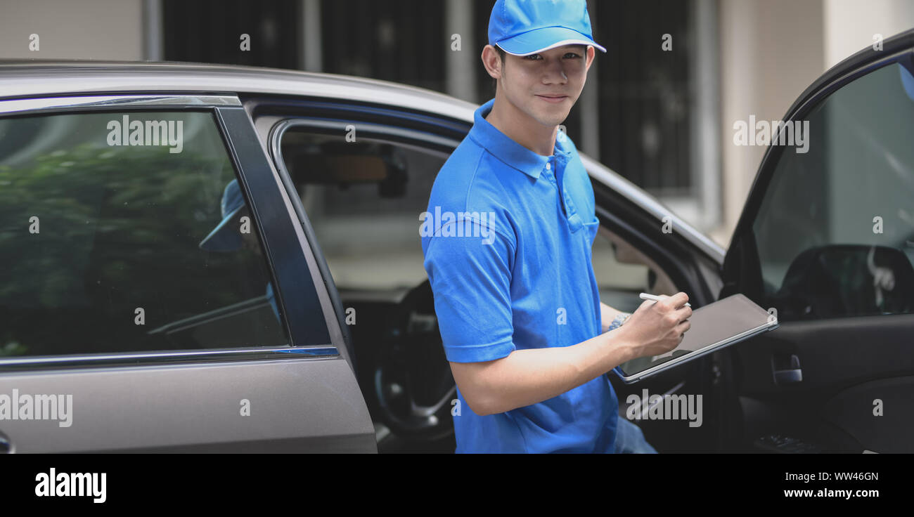 Young delivery man checking the products to customer while standing right next to his car. Stock Photo