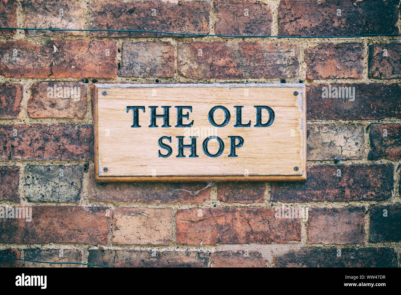 The old shop sign on a brick cottage wall. Little Comberton , Cotswolds, Wychavon district, Worcestershire, UK. Vintage filter applied Stock Photo