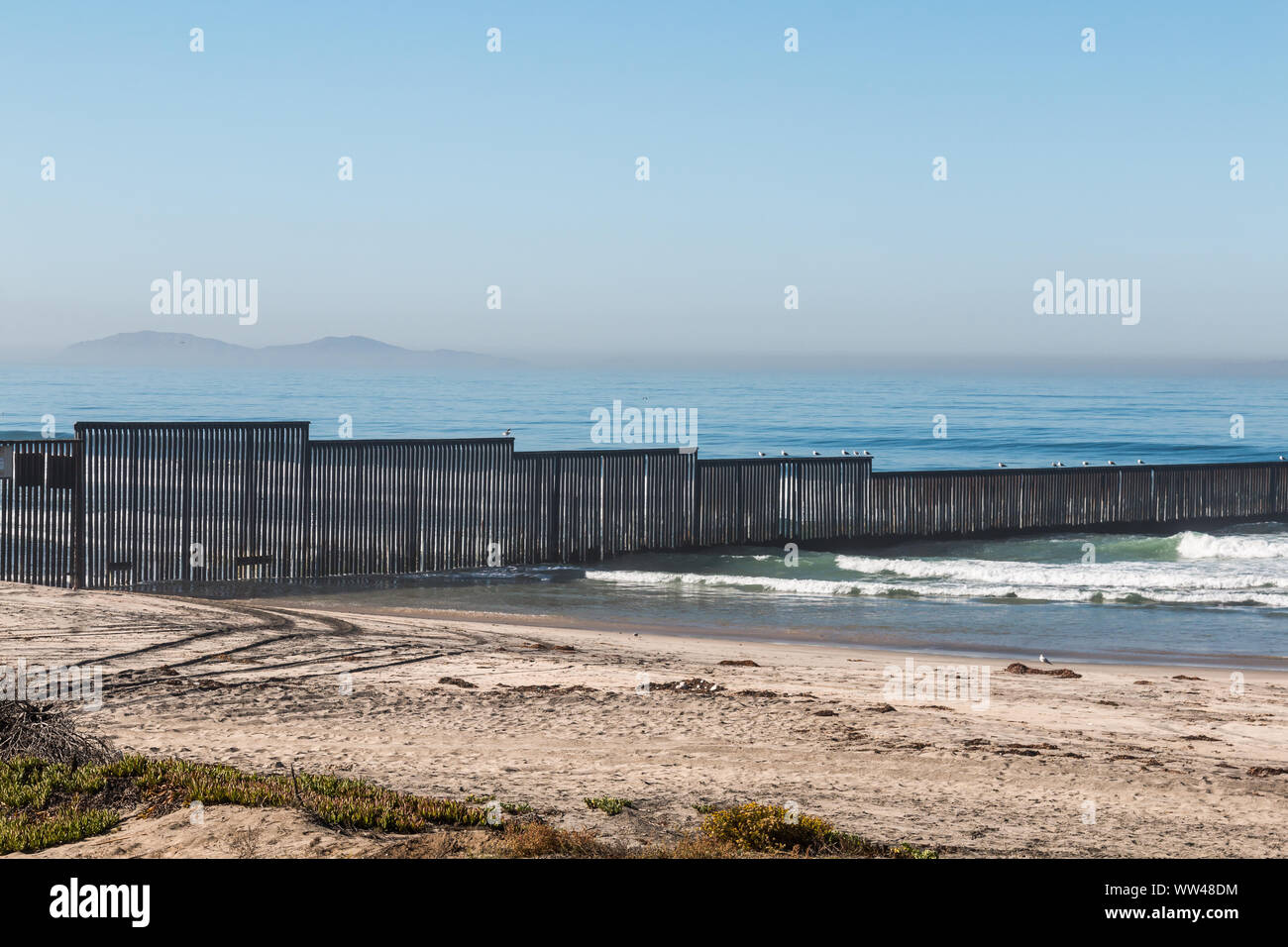 The international border wall separating Tijuana, Mexico from San Diego, California on the Border Field State Park beach with the Islas Los Coronados. Stock Photo