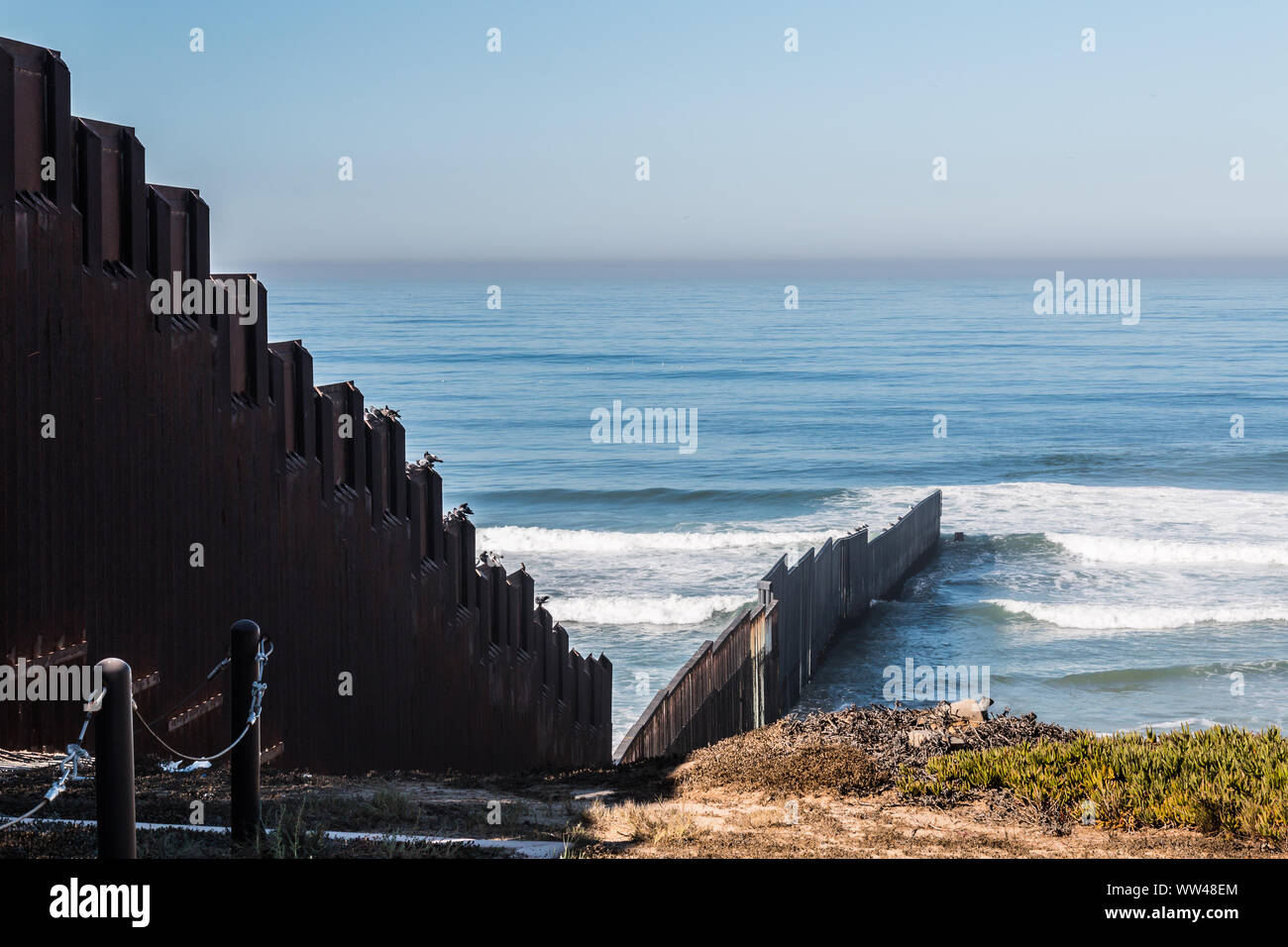 International border wall extending out into the Pacific ocean and separating San Diego, California from Tijuana, Mexico. Stock Photo