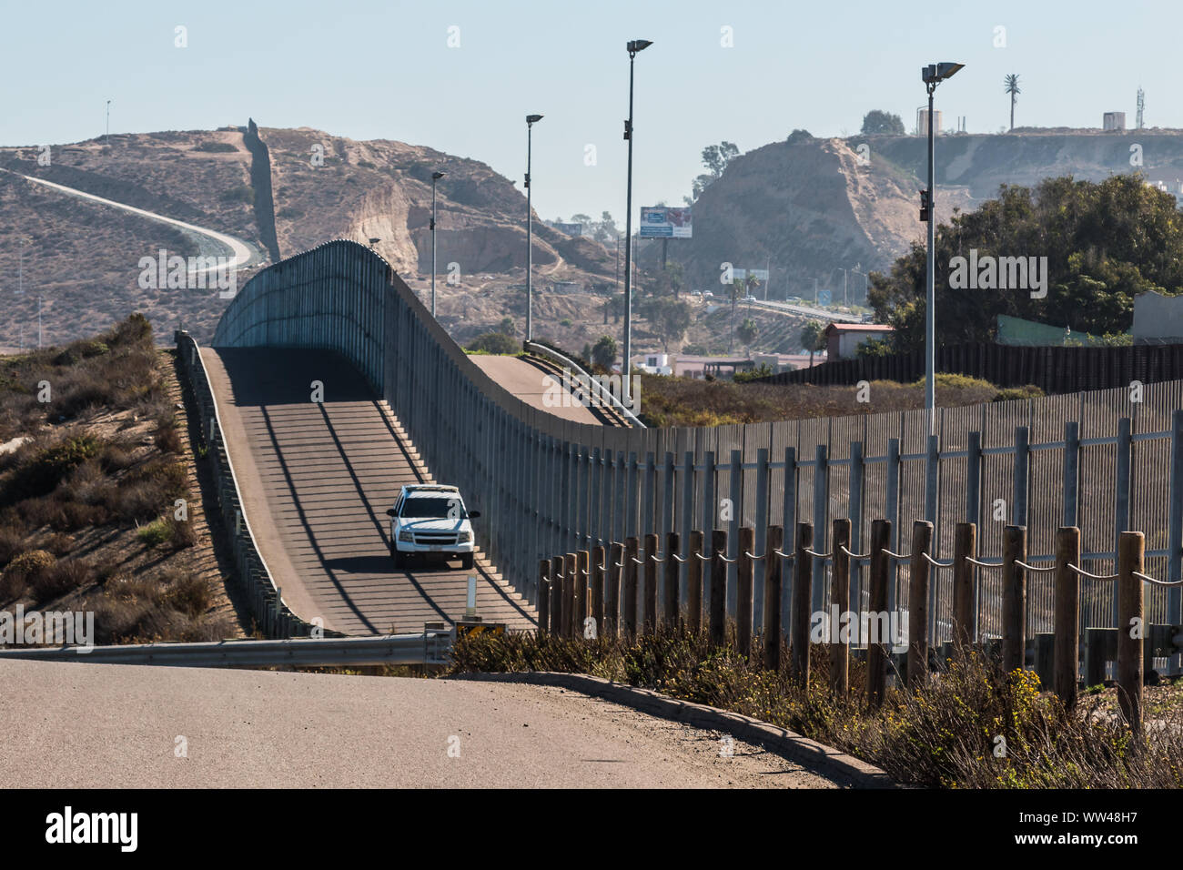 Border Patrol vehicle patrolling along the fence of the international border between San Diego, California and Tijuana, Mexico Stock Photo