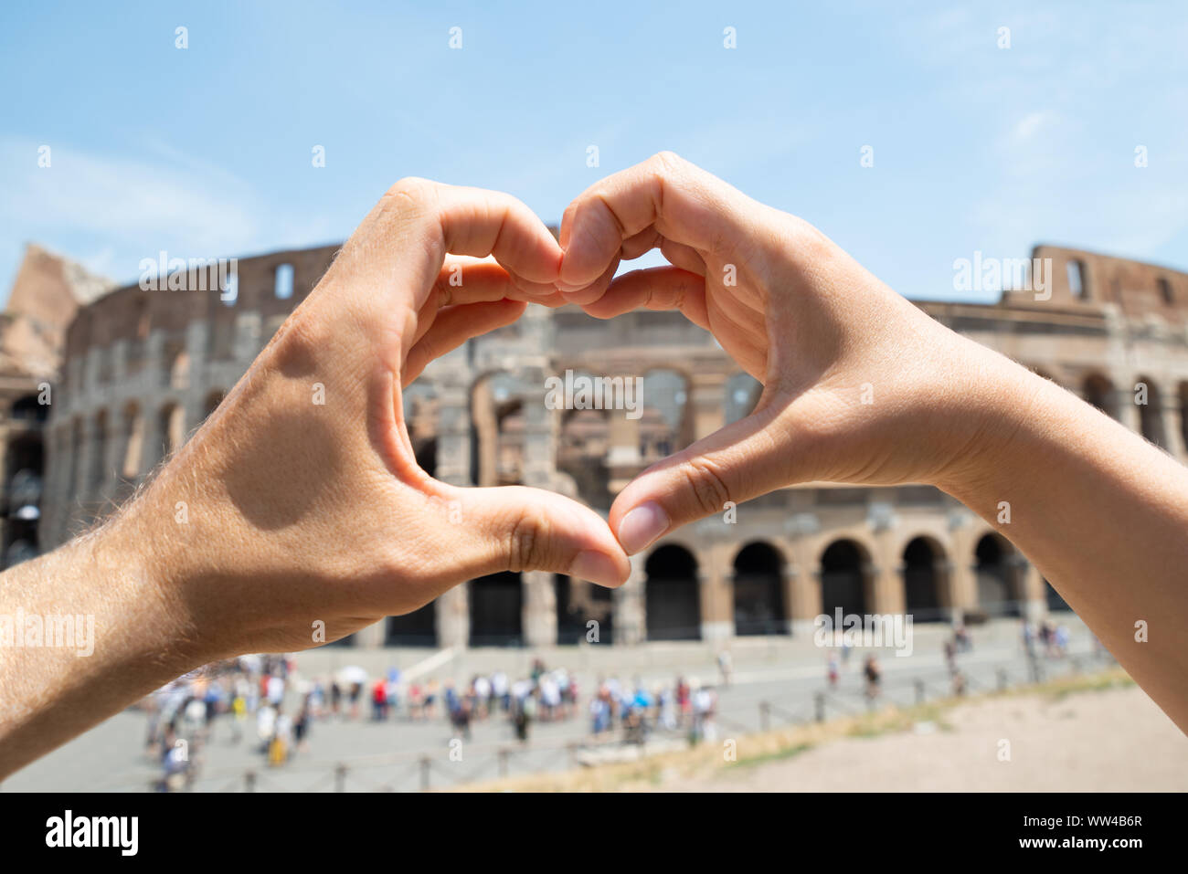 Couple Making Heart Shape In Front Of Colosseum, Italy Stock Photo