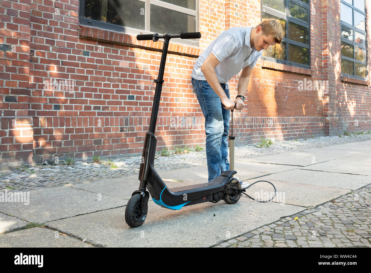 Man Pumping Air Into Tire On His EScooter Stock Photo Alamy