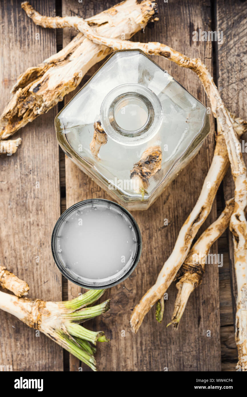 Alcohol tincture from fresh horseradish root.Raw horseradish roots on wooden background Stock Photo