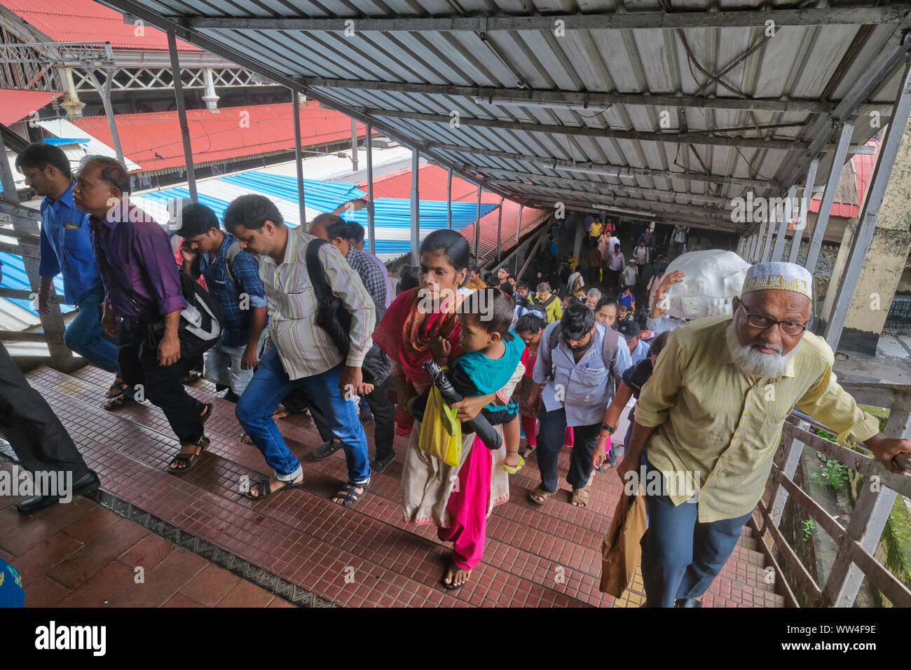 Passengers of local trains at Byculla Station in Mumbai, India, crossing over a bridge across the rail platforms Stock Photo