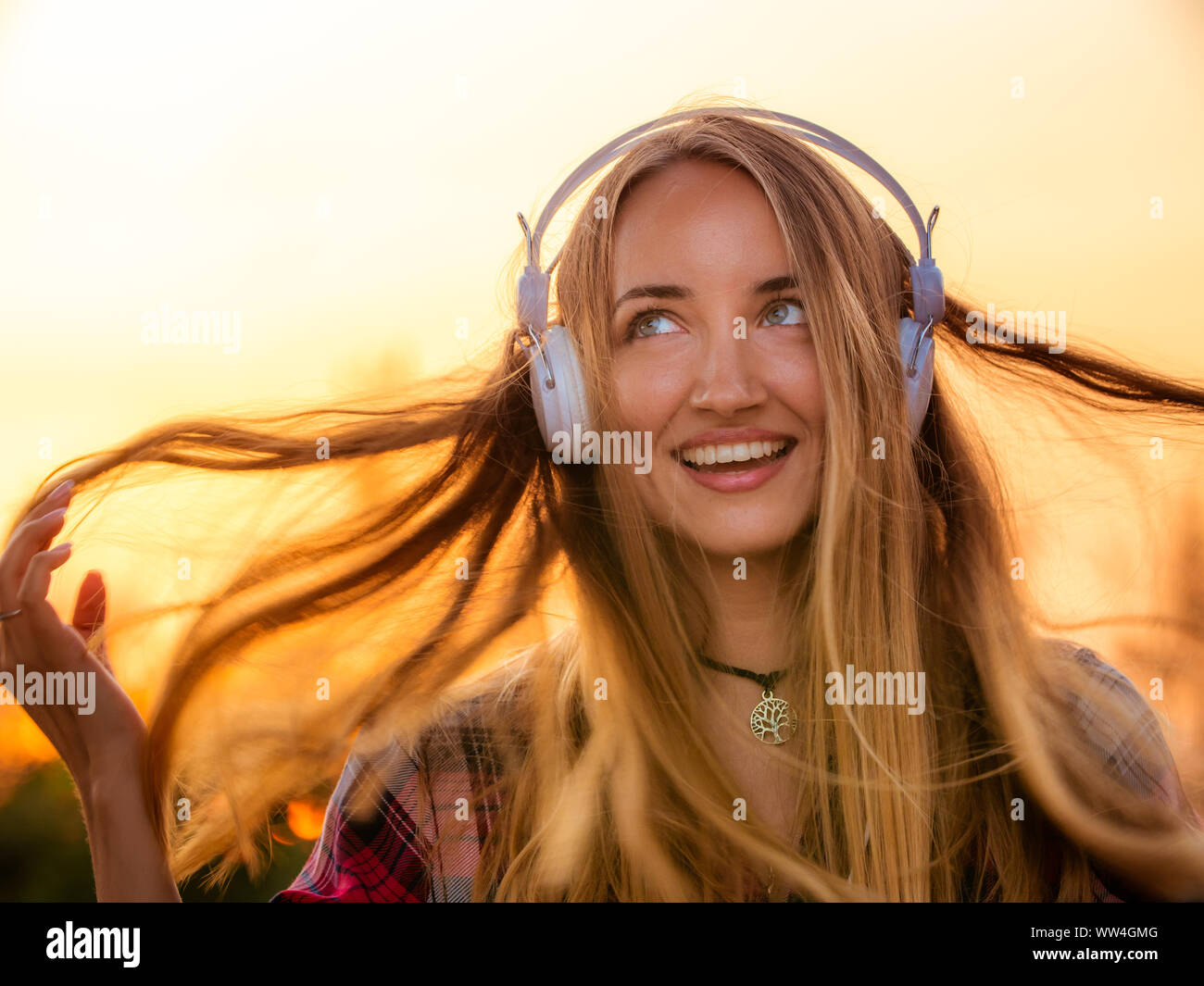 Happy young blonde woman with long hair and blue eyes listening to ...