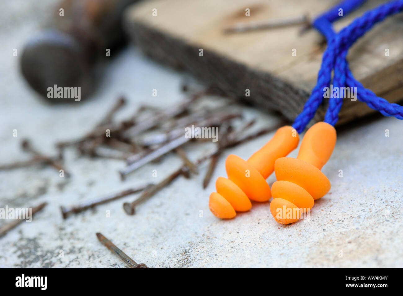 Orange reusable ear plugs in construction site, personal safety equipment concept. Outdoor shooting and shallow depth of field. Stock Photo