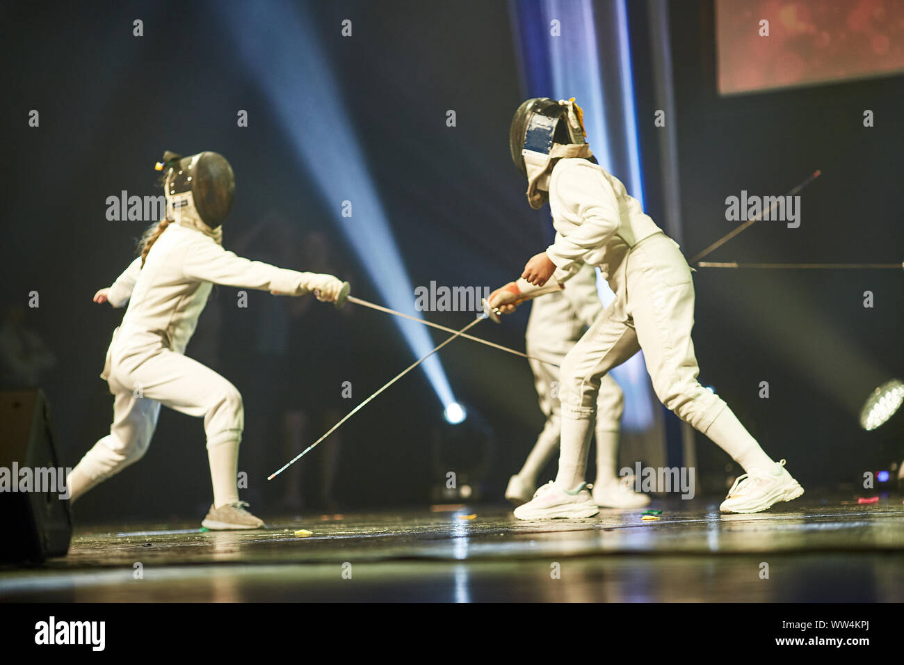 Junior Girls at a foil fencing athletes fight on professional sports arena with spectators and lens-flares Stock Photo