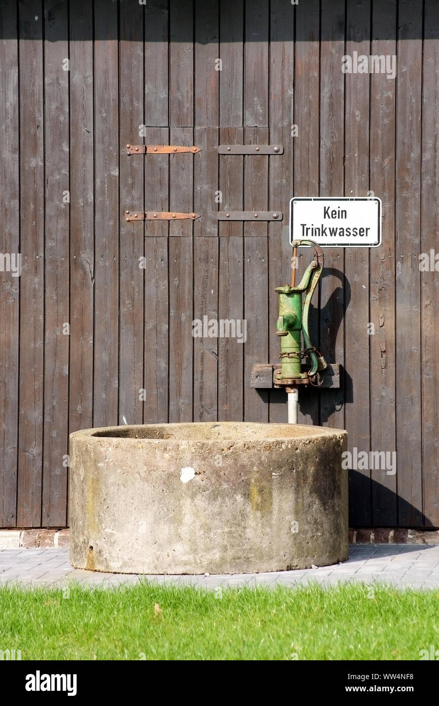 A well in front of a barn with an old rusted pump, Stock Photo