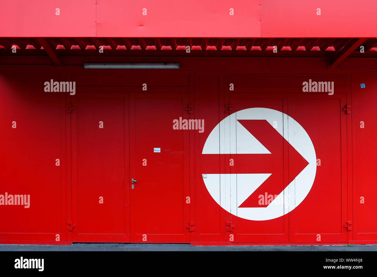 A rectangular red entrance sign with white writing on a vibrant red metal facade, Stock Photo