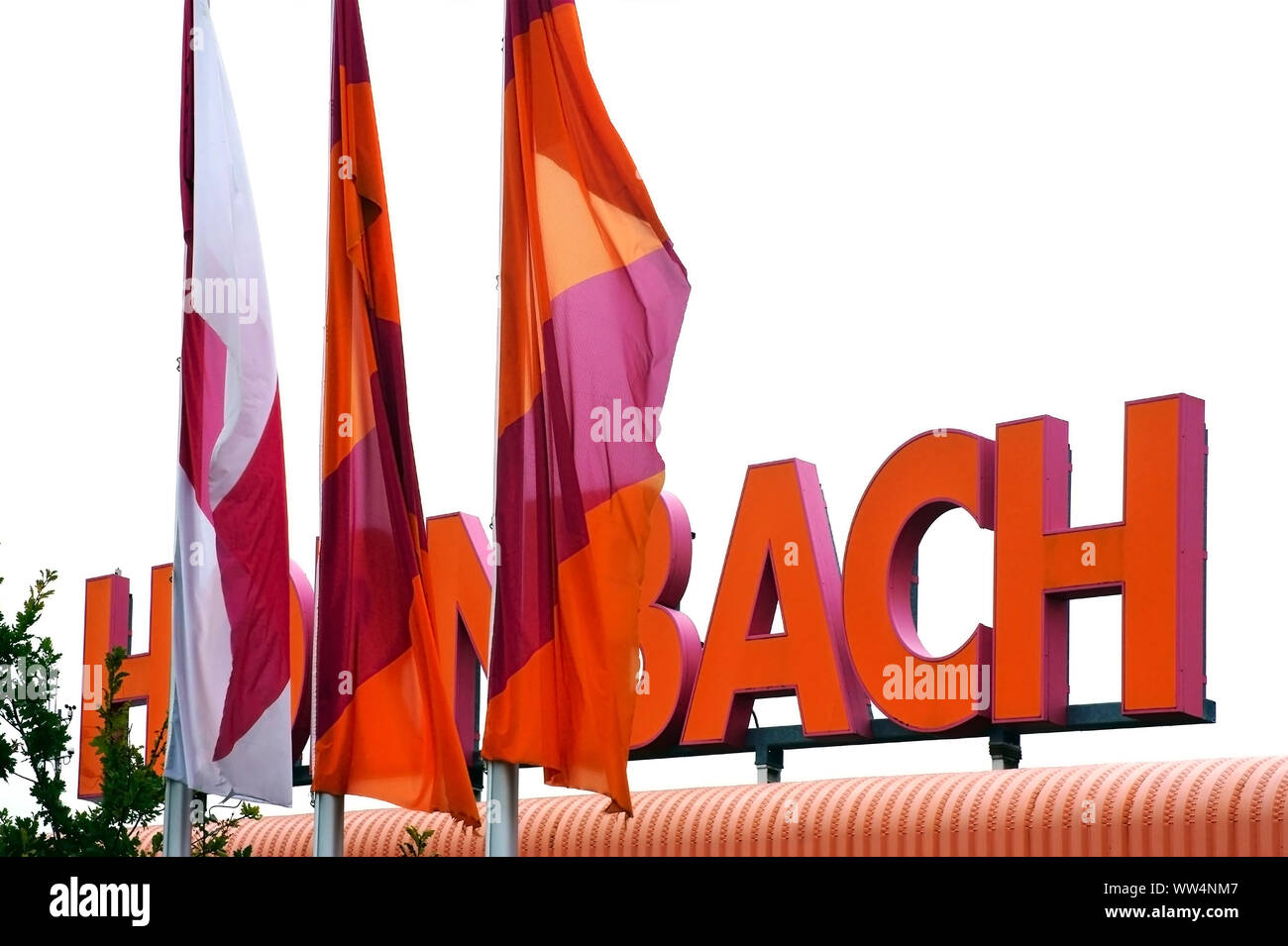 The orange bright company nameplate of the property market Hornbach with blowing flags, Stock Photo
