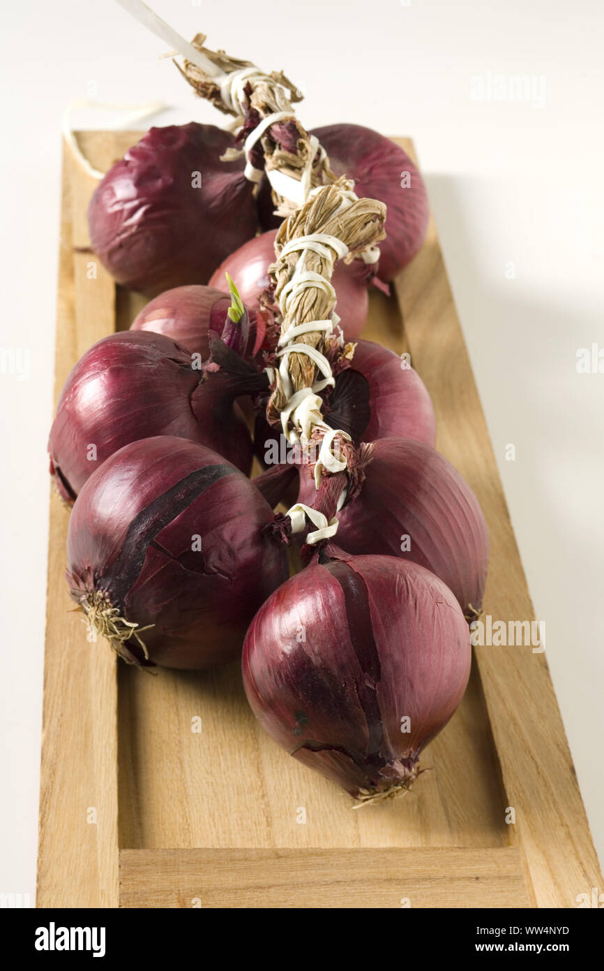 Red onion braid on wooden tray Stock Photo