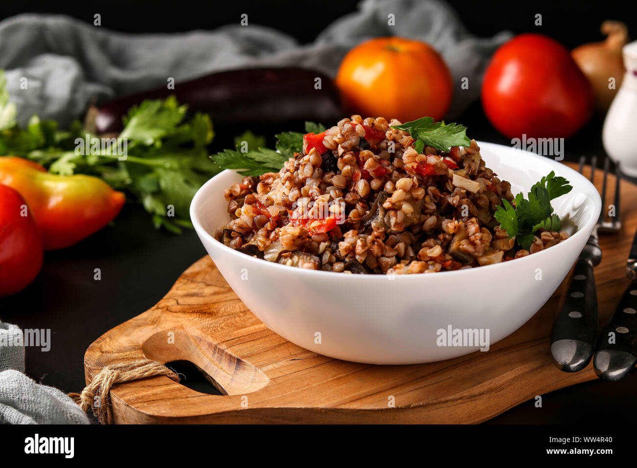 Healthy buckwheat cooked with vegetables in a white bowl on a dark