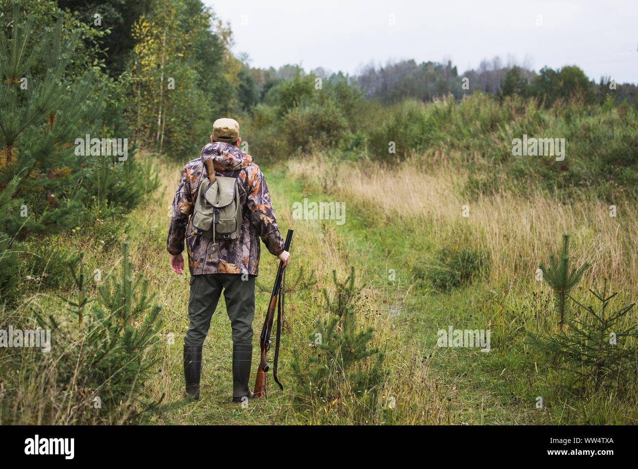 Hunter with a backpack and a hunting gun in the autumn forest. Stock Photo