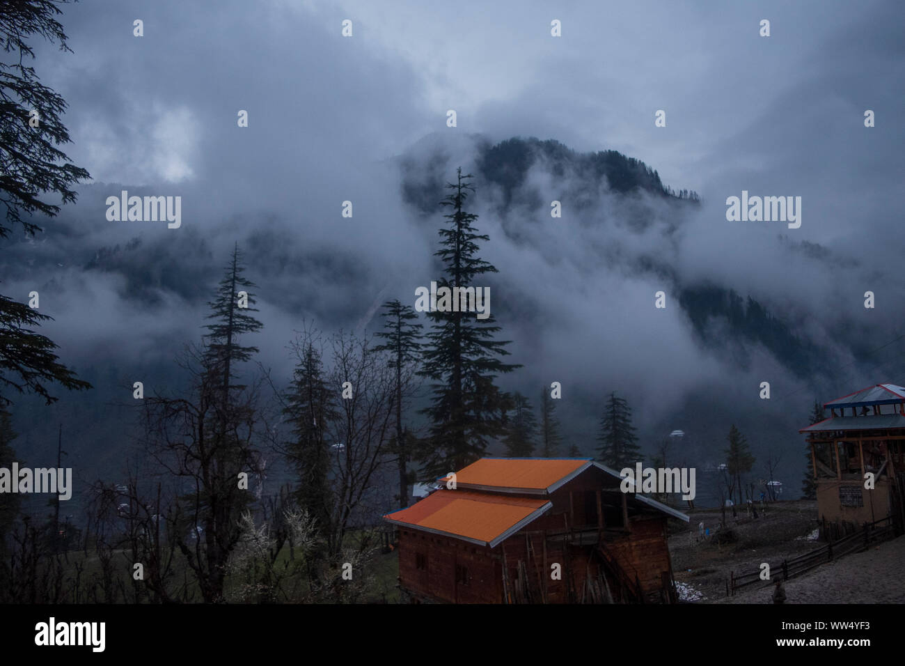 mountain hut up above with trees and clouds Stock Photo