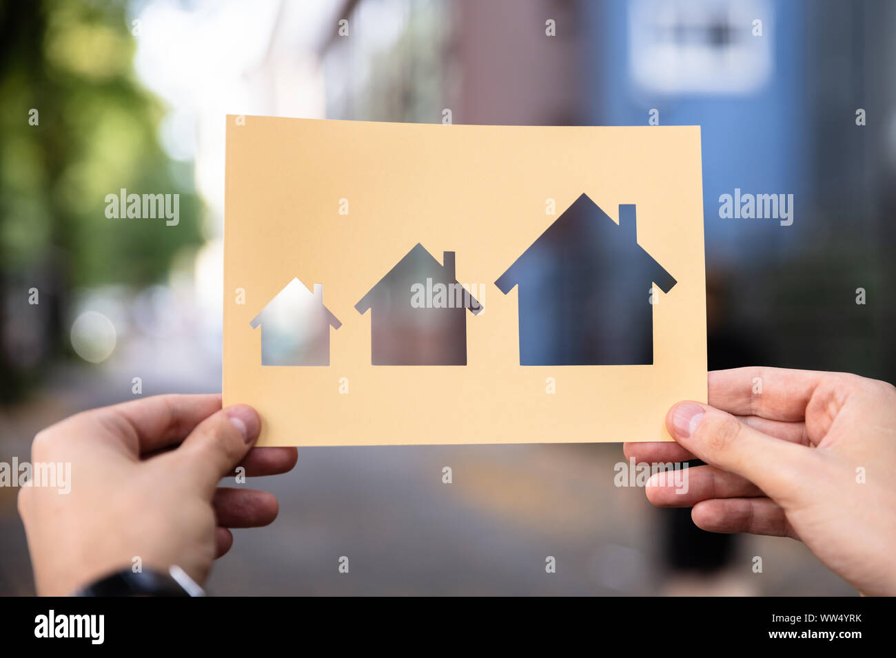 Hands Holding Paper With Cutout House Growth Outdoors Stock Photo