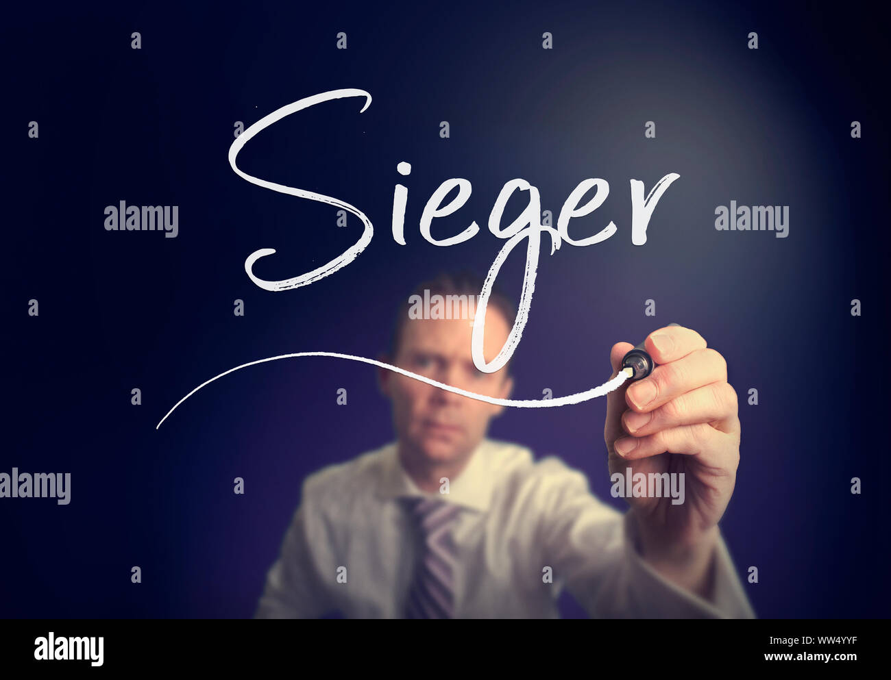 A businessman writing a Winner "Sieger" concept in German with a white pen on a clear screen. Stock Photo