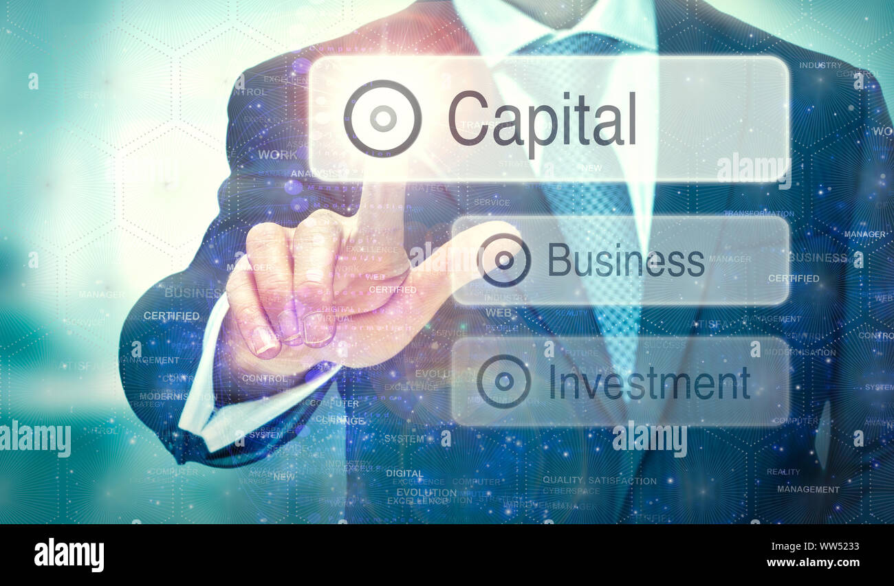 A businessman selecting a button on a futuristic display with a Capital concept written on it. Stock Photo