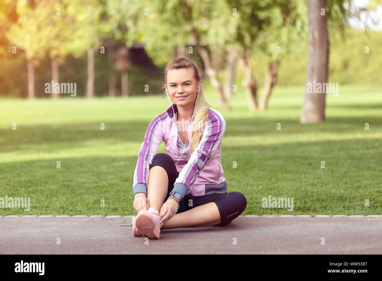 Mature fitness woman tie shoelaces in park Stock Photo