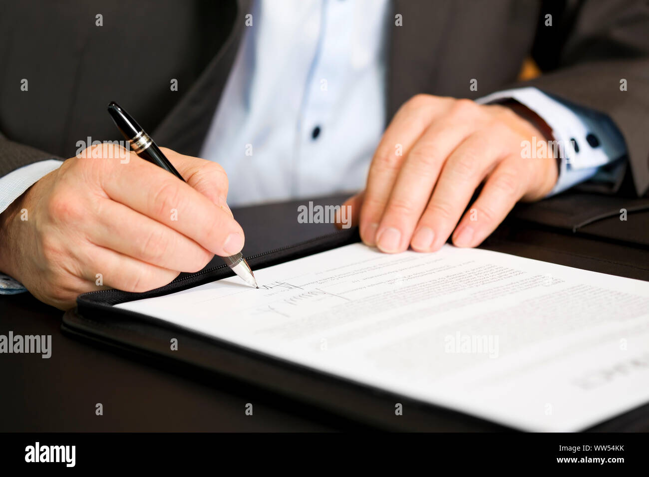 Business person signing a contract, focus on signature. Stock Photo