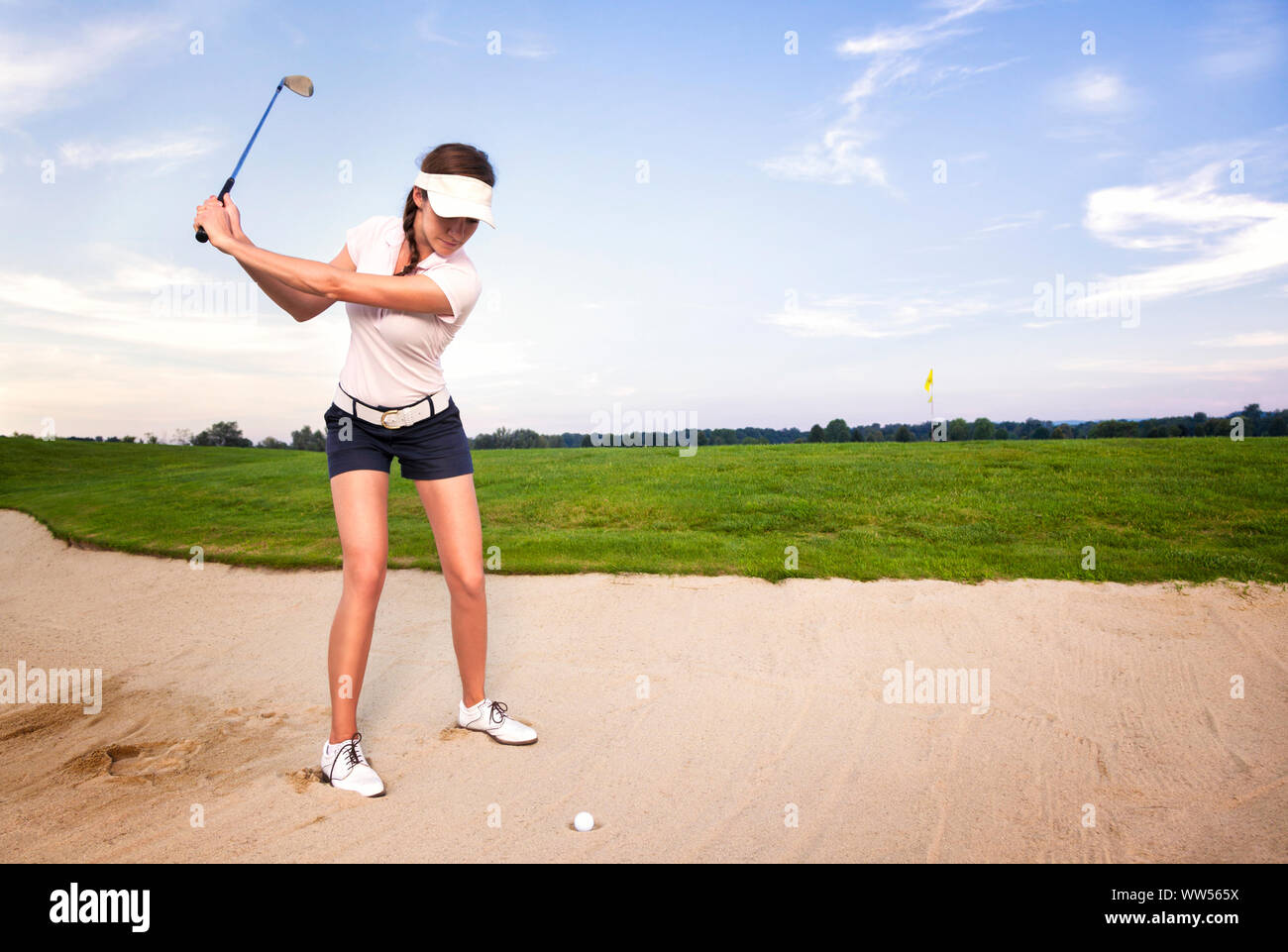 Woman golf player in sand trap preparing to hit the ball Stock Photo