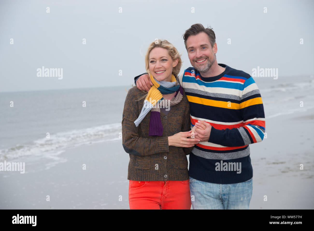 Half portrait of a couple embracing and going for a walk on the beach Stock Photo