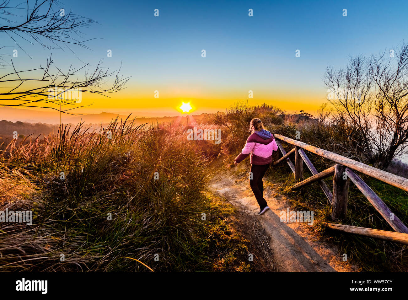 Woman walking along a footpath at sunset, Italy Stock Photo