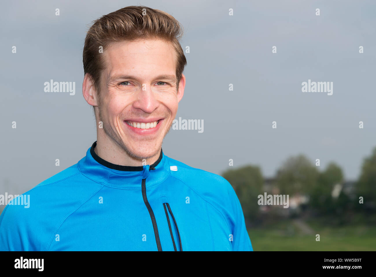 Man in blue tracksuit top smiling, looking at camera, portrait Stock Photo