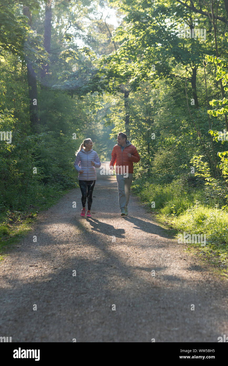 Couple running in forest in thick tracksuit tops Stock Photo