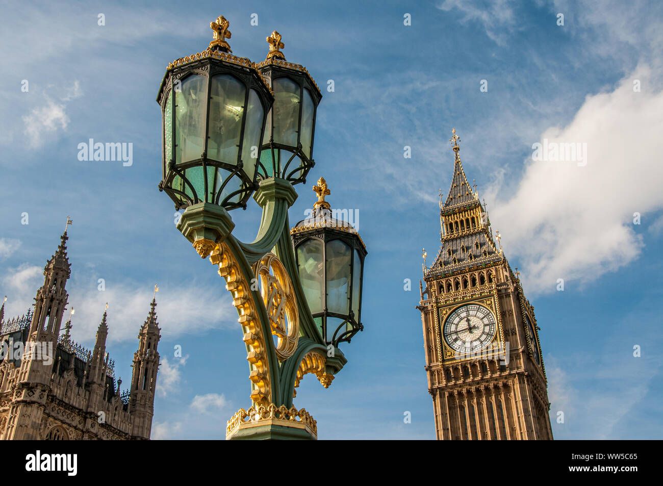 The Houses of Parliament and Big Ben with ornate street lamps on the Westminster Bridge in London in foreground. Stock Photo